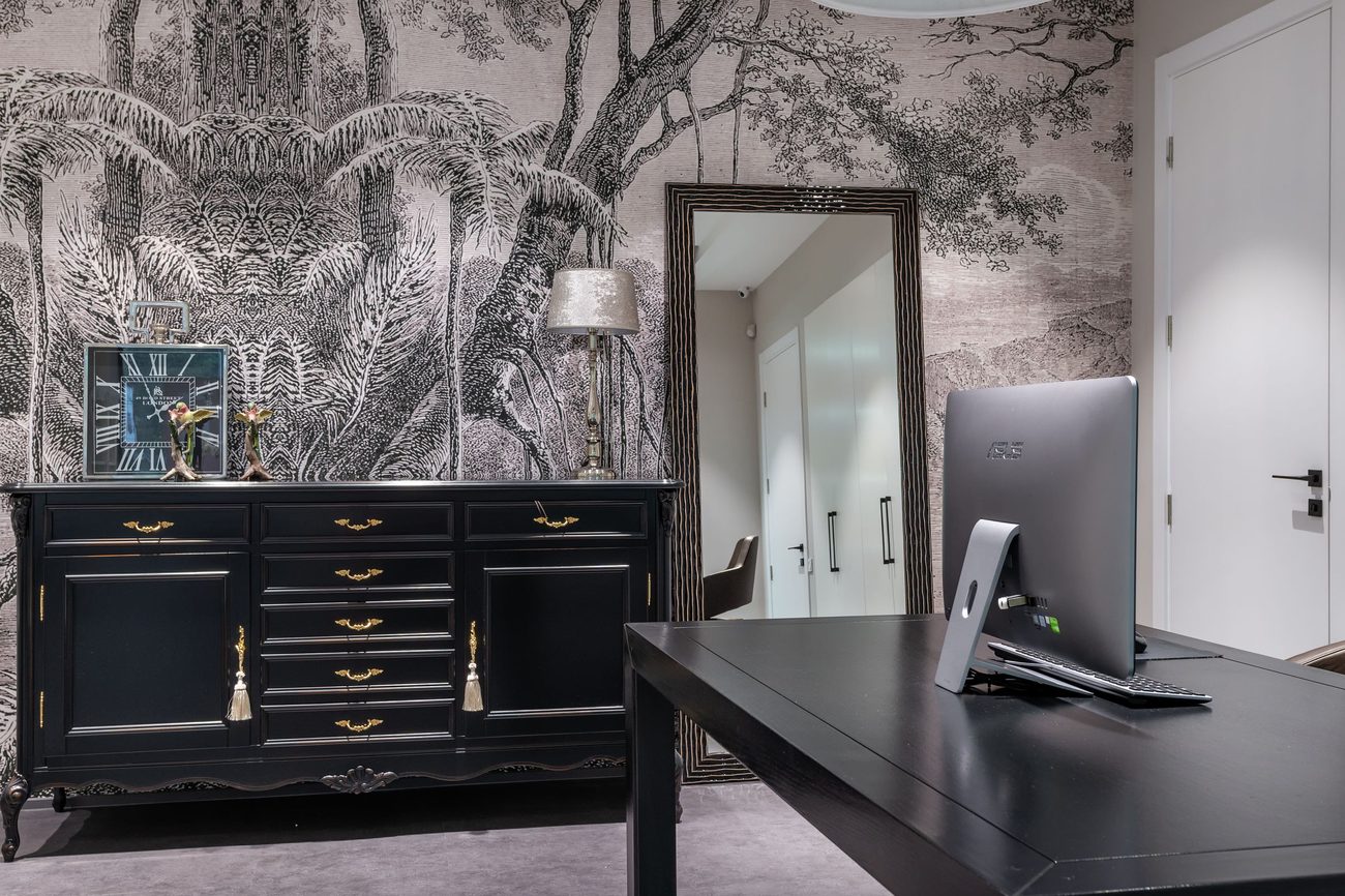 Home office with a black-and-white engraved tree mural wallpaper aligned cleanly across the wall behind a dark sideboard