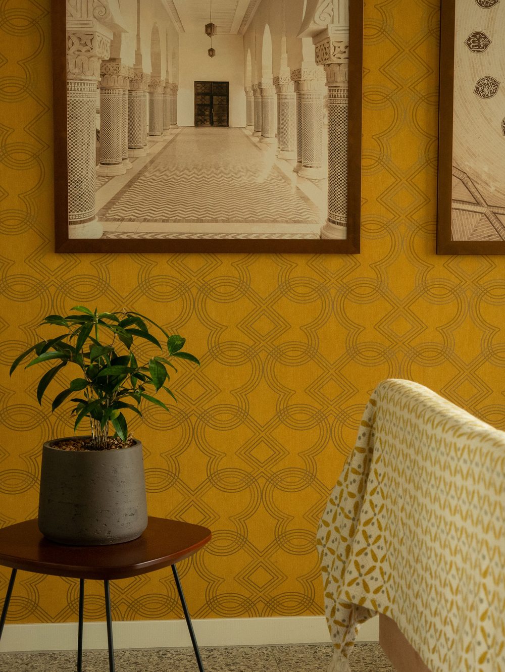 Sitting room with mustard-yellow interlocking geometric trellis wallpaper and a potted plant