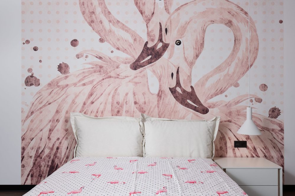 Bedroom with a dusty-pink flamingo mural above a made bed