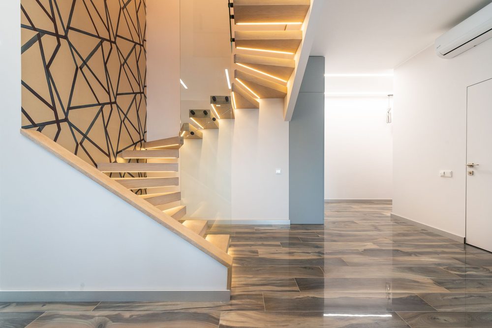 Modern staircase with a bold black geometric web-pattern wallpaper on a mustard wall