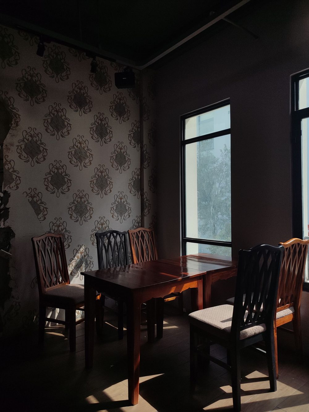 Dining corner with grey-and-brown damask medallion wallpaper and a dark wood table