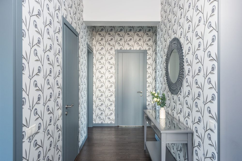 Corridor with grey-and-white floral-stem wallpaper, a console table and a round mirror