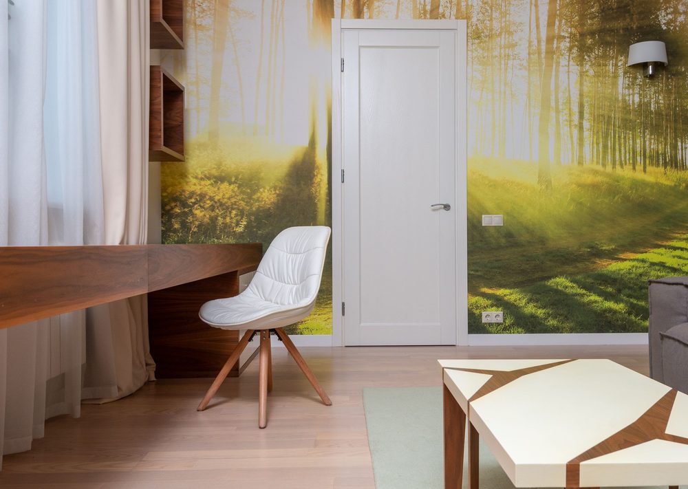 Study nook with a full-height birch-forest mural on the feature wall beside a white armchair
