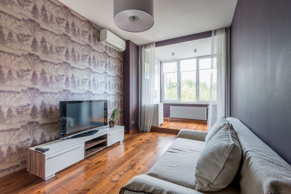 Living room with a tree-silhouette patterned accent wall behind a media console